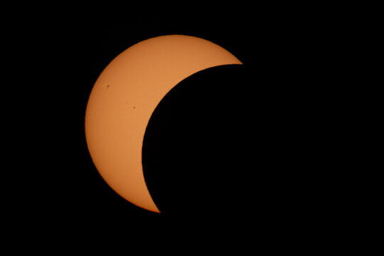 Aerial view of a partial solar eclipse showing the moon obscuring a portion of the sun against a dark sky in Mulhouse, Grand Est, France.