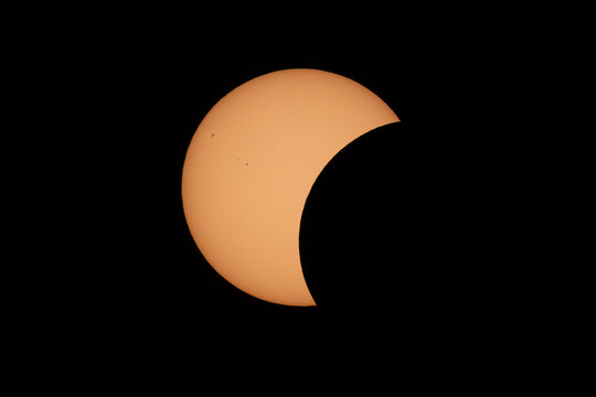 Aerial view of a partial solar eclipse showing the moon partially covering the sun in the dark sky over Mulhouse, Grand Est, France.