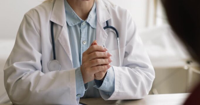 Female doctor explaining diagnosis to patient on consultation meeting in medical office, sitting at workplace, speaking, moving hands, using gestures for expressiveness