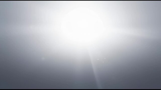 Bright white sun flare against a soft, hazy, dark grey background