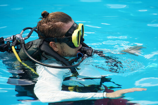 A professional diver and a novice practice diving in a pool.