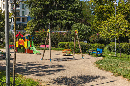 Albania, Tirana 06 09 2025: Children playground with swings and play equipment surrounded by green trees at Ismail Qemali Park in Tirana on a sunny day.