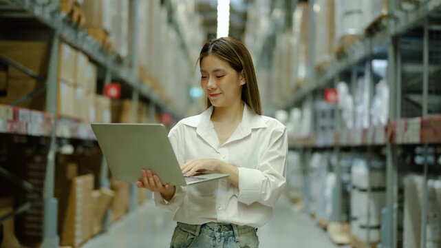 Asian female warehouse manager holding laptop, thinking, and finding a solution for inventory management. Modern logistics business, smart stock control, and successful female entrepreneur concept.
