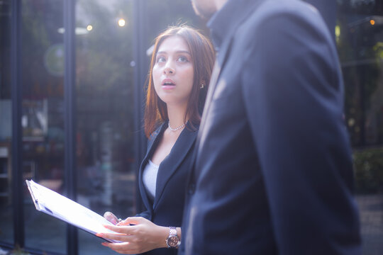 Business colleagues reviewing documents on tablet while walking outside office building