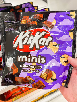 A hand holding a purple bag of Kit Kat Minis Unwrapped milk chocolate Halloween candy - August 8. 2026, Portland Oregon, USA