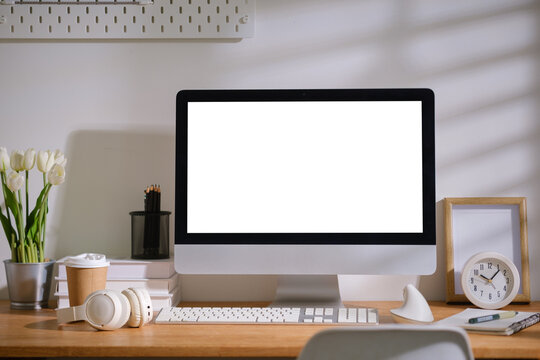 Blank desktop monitor displayed on a modern wooden desk for a digital mockup.