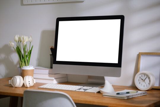 Blank desktop monitor displayed on a modern wooden desk for a digital mockup.