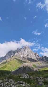 Stunning vertical view of majestic Caucasus mountains in Juta, Georgia, on a sunny summer day with blue sky and clouds.