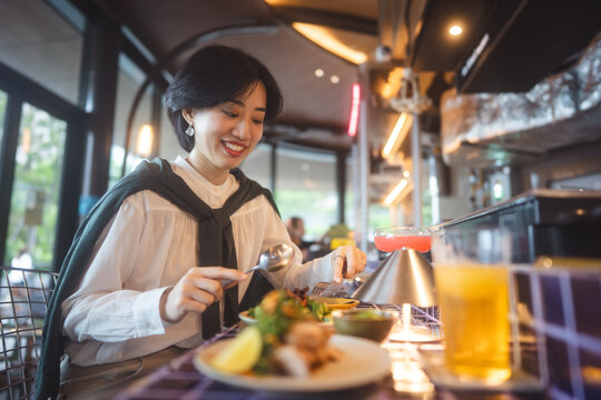 Adult asian business woman relax drink and food at trendy modern Thai restaurant bar enjoy tasty dinner alone urban nightlife