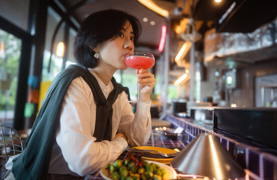 Adult asian business woman relax drink and food at trendy modern Thai restaurant bar enjoy tasty dinner alone urban nightlife