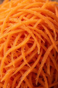 Macro view of freshly grated carrot shreds. Vibrant orange julienned vegetable pile creates a textured background for food content. Healthy ingredient for salads and cooking.