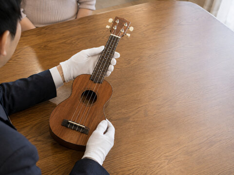 Professional Appraiser Inspecting a Small String Instrument During a Home Visit