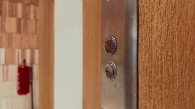 Close-Up Of Hand Pressing Modern Elevator Buttons On Wooden Panel In Lobby Interior Design Detail