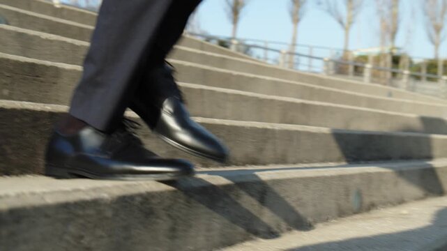 Сlose-up of the legs of a businessman in black classic shoes going down the stairs. Legs of a businessman in fashionable shoes walking quickly down the steps. Stylish men wears.