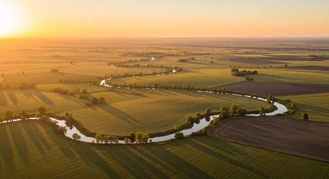 Scenic aerial view of lush green farmland with winding river at sunset showcasing rural landscape and agricultural fields under warm golden light