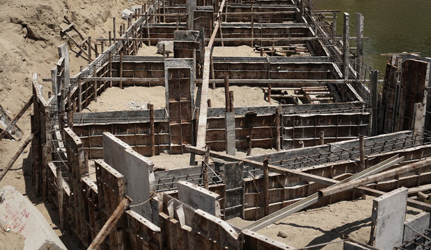 Building process city levee. Exposed foundation rebar grid at site, standing formwork and concrete footings