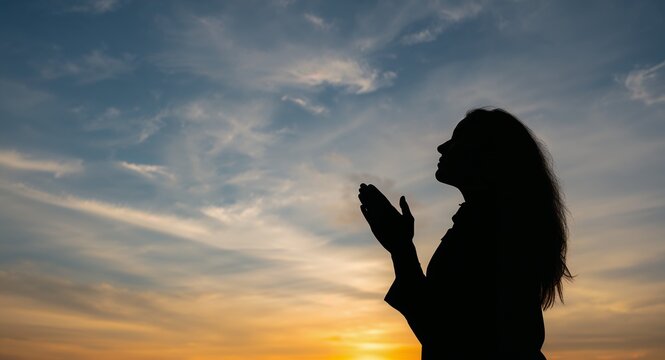 Silhouette of woman praying over beautiful sky background with copy space on left, featuring Conveying and Spiritual, with Devotion, as a contemporary creative concept, for editorial and marketing use
