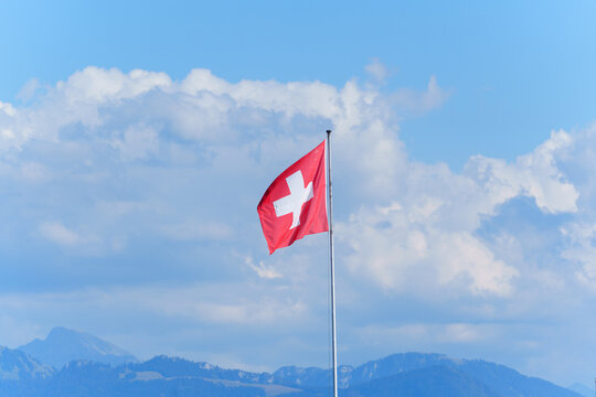 National Flag of Switzerland Waving Proudly Against a Cloudy Sky in Morges