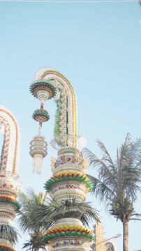 Vibrant Penjor Arch with Butterfly Detail and Hanging Green Ornament Against Clear Sky &mdash; Traditional Bali Cultural Celebration