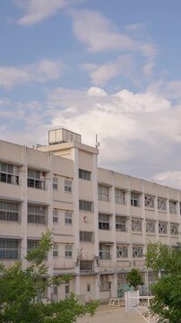 柔らかい光に包まれる夕暮れ時の校舎と背後で湧き上がる大きな入道雲