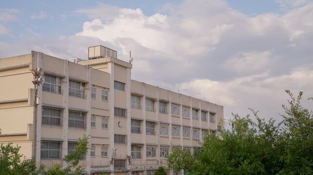 柔らかい光に包まれる夕暮れ時の校舎と背後で湧き上がる大きな入道雲
