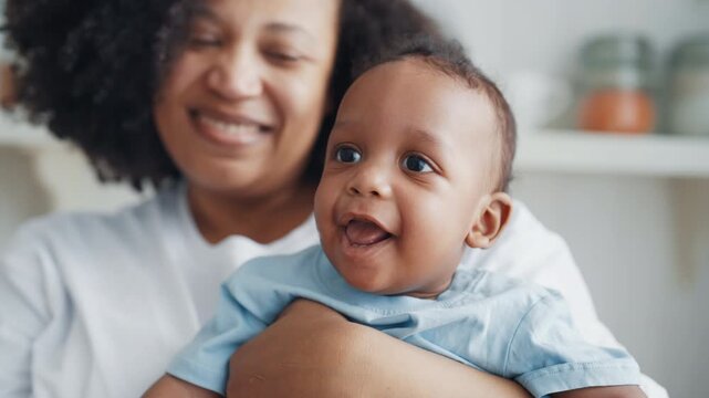 Portrait of cute african infant girl or boy, mother holding baby in hands. Childhood and motherhood, happy family moments, single woman parenting baby, african american ethnicity, mixed race children
