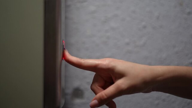 Female finger with manicure pressing elevator button to summon lift, which arrives, button lights up red after being pushed, indicating call has registered and elevator coming, close-up, slow motion.