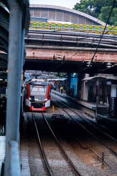 Jakarta, Indonesia - August 16, 2026: KAI Commuter CLI 225 train stops at Sudirman Station beneath the Sudirman Street bridge.