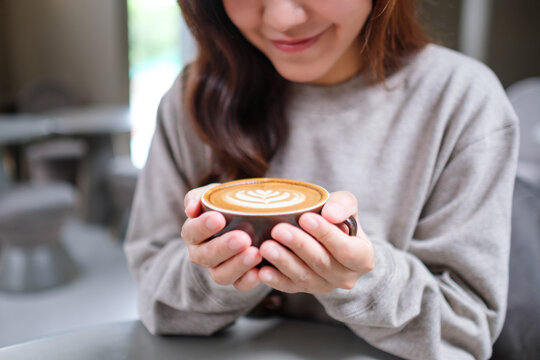 Closeup image of a woman holding a cup of hot latte coffee