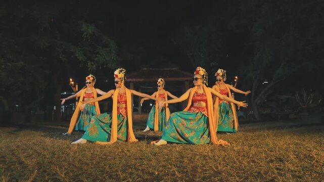 Group of Indonesian Dancers in Traditional Costumes and Sunglasses Performing at Night