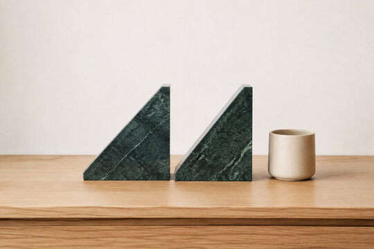 Two identical triangular bookends in row on oak desk with ceramic cup, minimalist desk organization concept