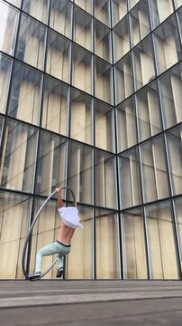 Dynamic and vibrant performance of a Cyr Wheel within urban architecture, vertical video. Concept of individuality, creativity and self-confidence