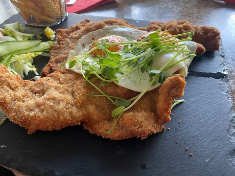 Wiener Schnitzel vom Kalb mit Spiegelei, frischem Salat und knusprigen Pommes frites. Klassisches Restaurantgericht, &ouml;sterreichische K&uuml;che, Hausmannskost und authentische Food-Fotografie.