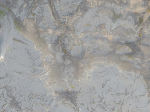 Aerial view of volcanic landscape with intricate river patterns and patches of green moss in the rugged terrain of Iceland.