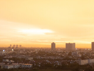 Fototapeta premium City skyline at dawn, showcasing residential areas and tall buildings under a warm orange sky.