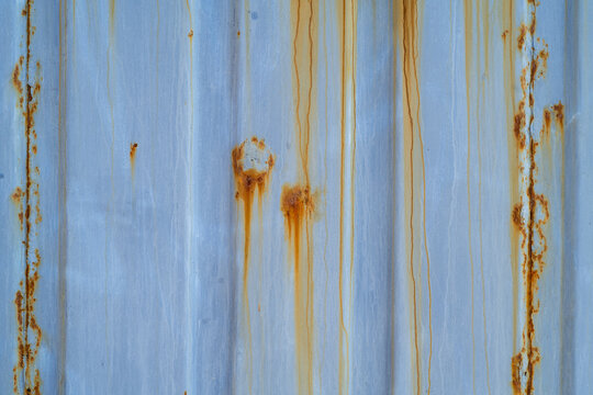 Pale blue painted metal texture background with orange rust streaks and corrosion
