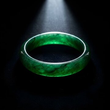 Luxury green jadeite bangle bracelet glowing under a dramatic top spotlight against black velvet background, symbolizing Chinese culture and fortune.