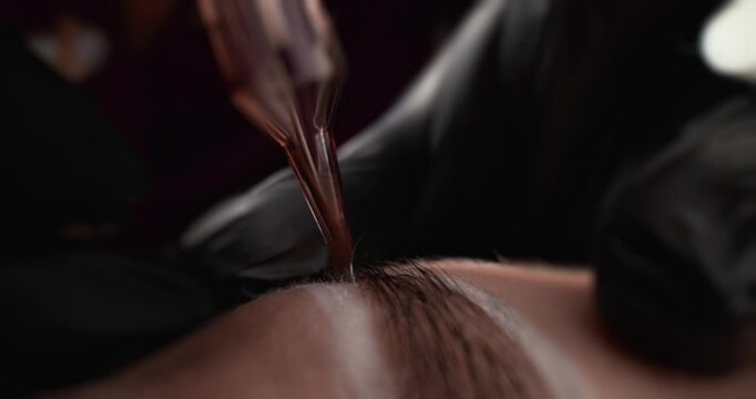 Closeup of eyebrow microblading procedure on client forehead in salon treatment setting.