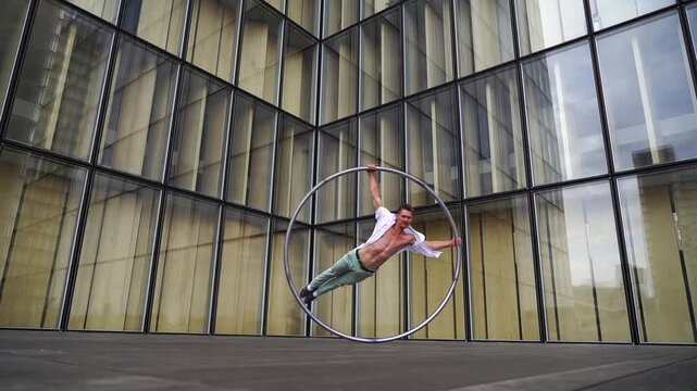 Dynamic and vibrant performance of a Cyr Wheel within urban architecture. Concept of individuality, creativity and self-confidence