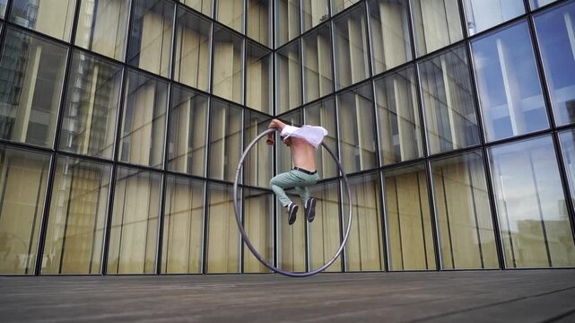 Dynamic and vibrant performance of a Cyr Wheel within urban architecture. Concept of individuality, creativity and self-confidence