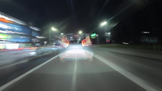Dynamic night city time-lapse filmed from a moving car, showing bright light trails from traffic and streetlights. Perfect for urban, travel, or nightlife themed video projects.