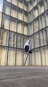 Dynamic and vibrant performance of a Cyr Wheel within urban architecture, vertical video. Concept of originality, creativity and outstanding