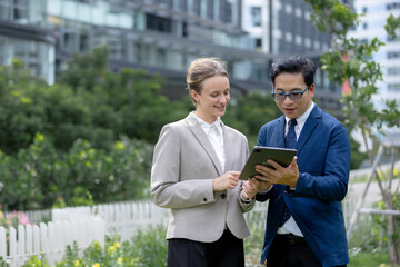 Fototapeta premium Business professionals reviewing tablet together outdoors, representing teamwork, collaboration, digital technology, communication, consulting, planning, partnership, corporate strategy.