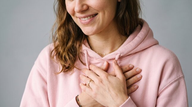 Happy woman smiling with hands clasped in a cozy pink sweater