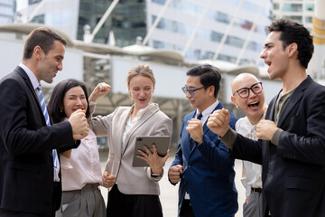 Obraz premium Diverse business professionals celebrating success outdoors with raised fists, showing teamwork, achievement, corporate victory, motivation, collaboration and positive team spirit.