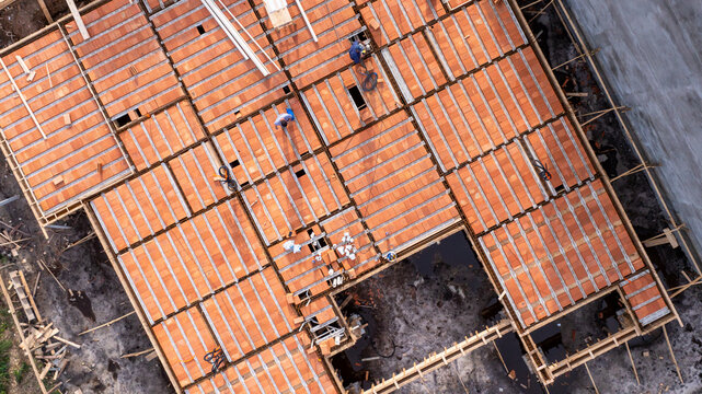 Aerial view of a residential construction site featuring workers installing pre-cast concrete beams and clay tiles for a new house in Florianopolis, Santa Catarina, Brazil.