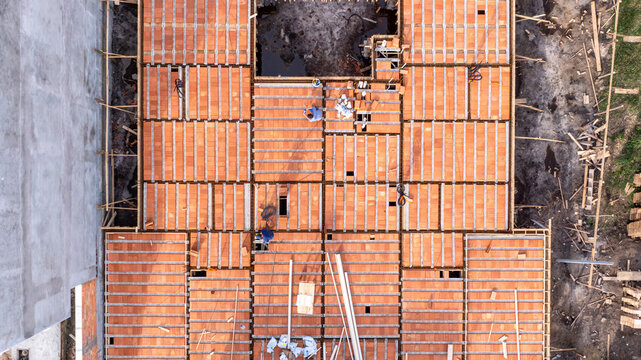 Aerial view of a modern residential construction site featuring workers installing pre-cast concrete beams and ceramic blocks in Florianopolis, Santa Catarina, Brazil.