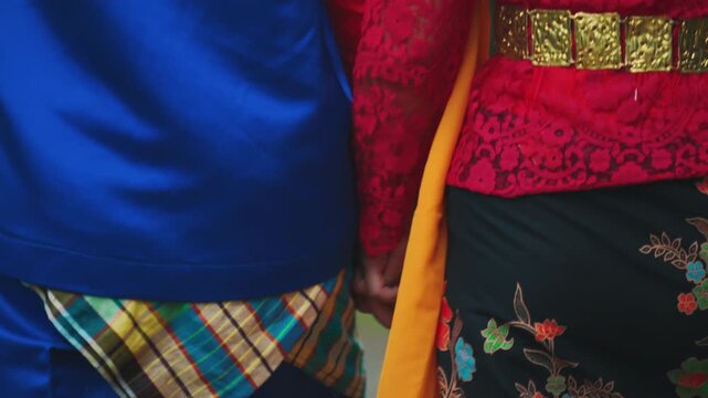Detailed Shot of Couple Holding Hands, Highlighting Traditional Garments