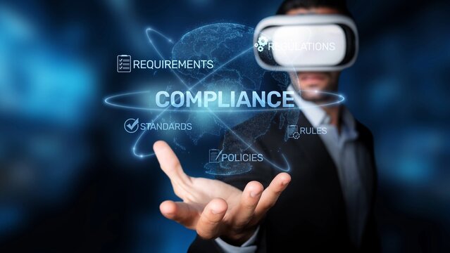 A businessman in virtual reality goggles holds out a hand, immersed in a digital environment showcasing various terms related to compliance and regulations. Raster