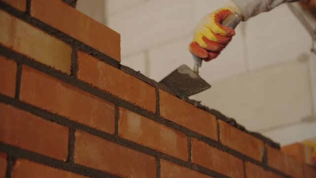 Worker checking level of newly built brick wall
